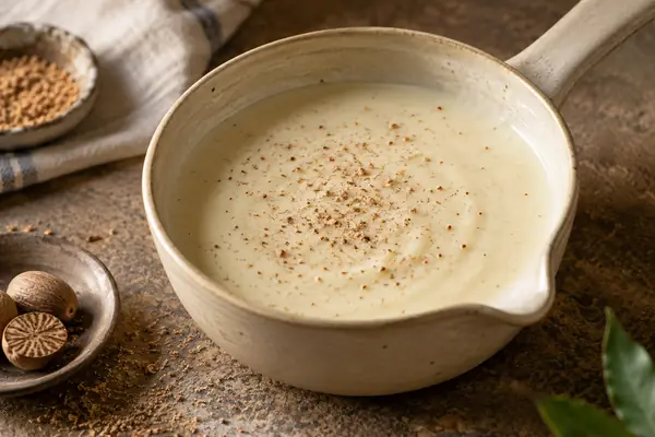 Molho béchamel cremoso num tacho com noz-moscada por cima